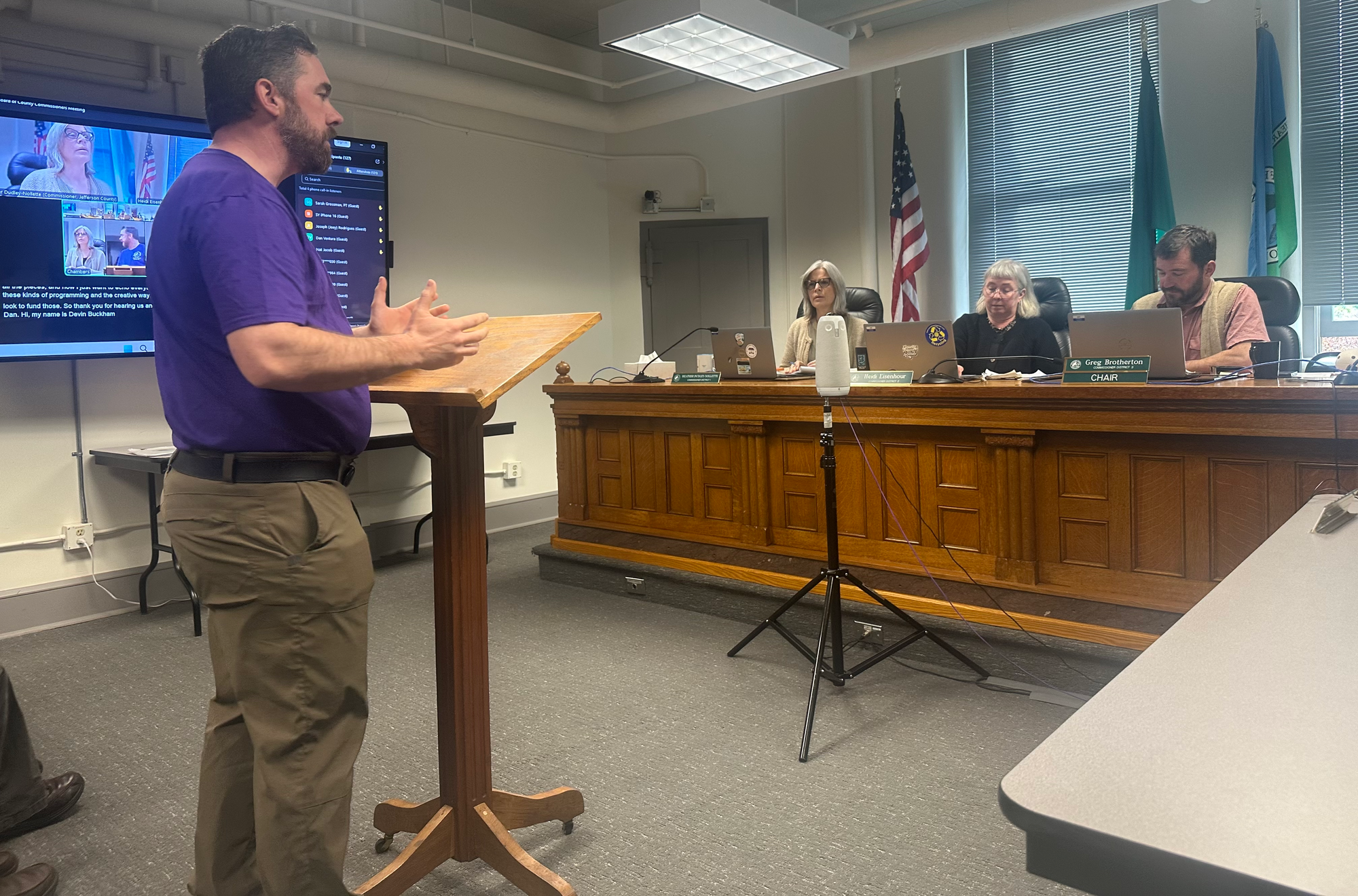 Devon Buckham stands at a lectern and addresses the BOCC