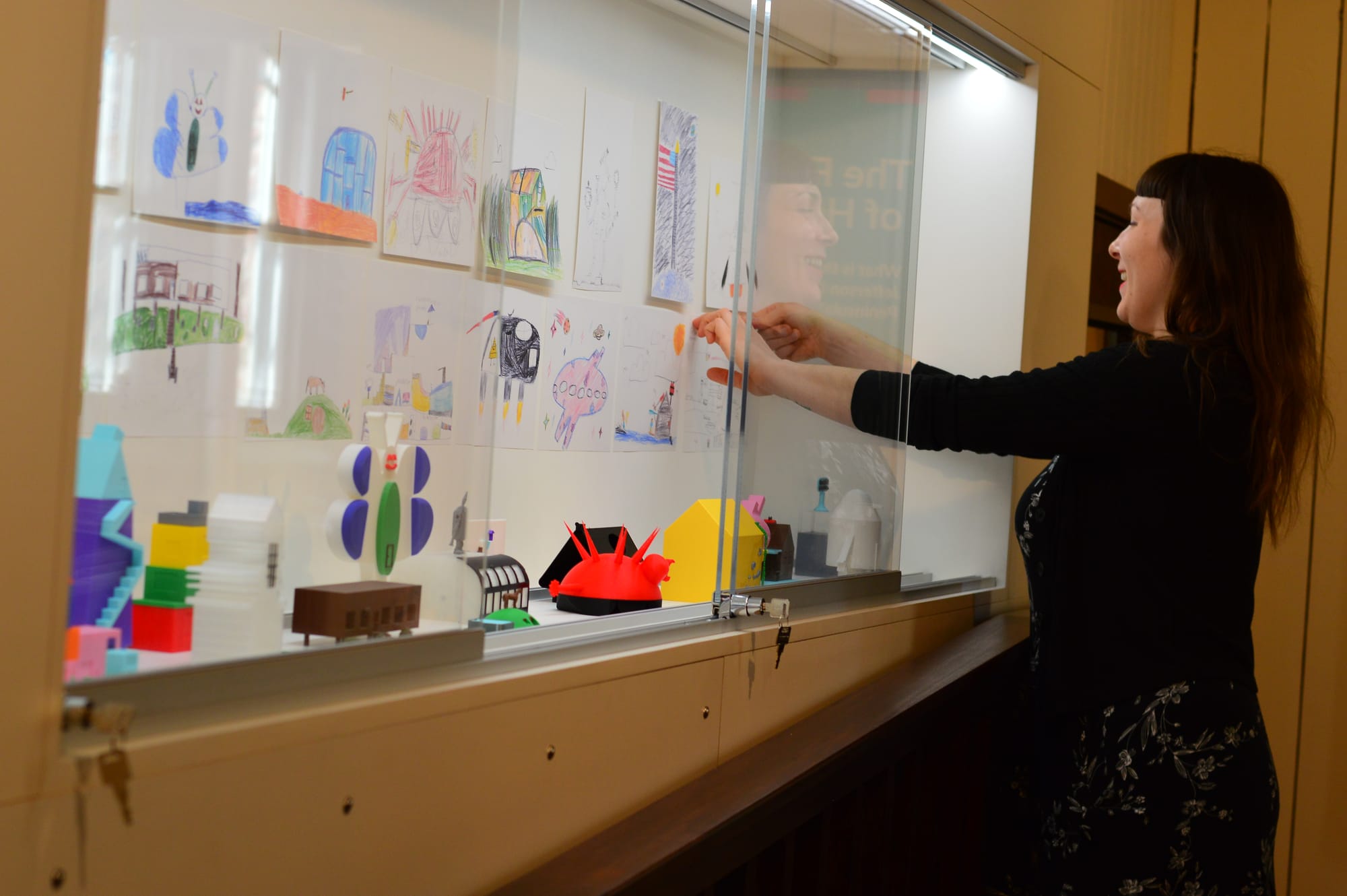 Kelsey Caudebec arranges sculptures and pictures of colorful homes designed by children