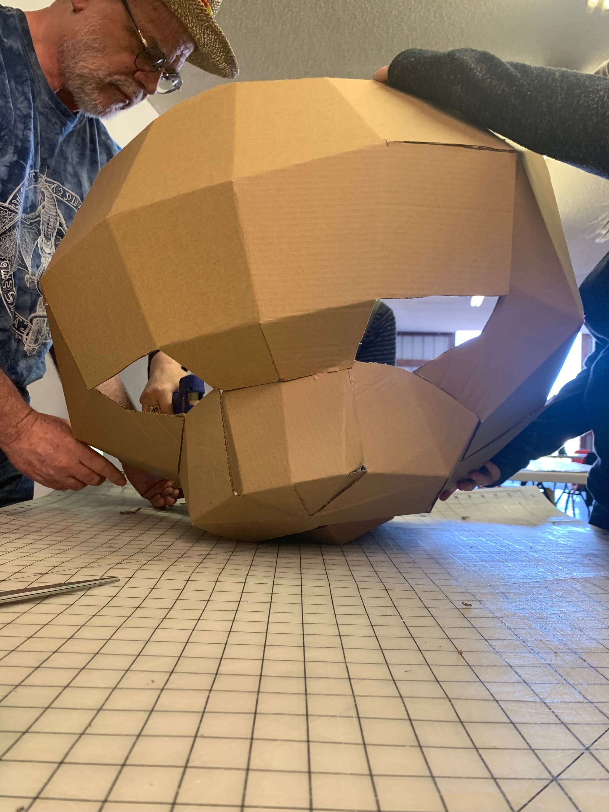 Artist Thaddeus Jurczynski works on large cat puppet made of cardboard