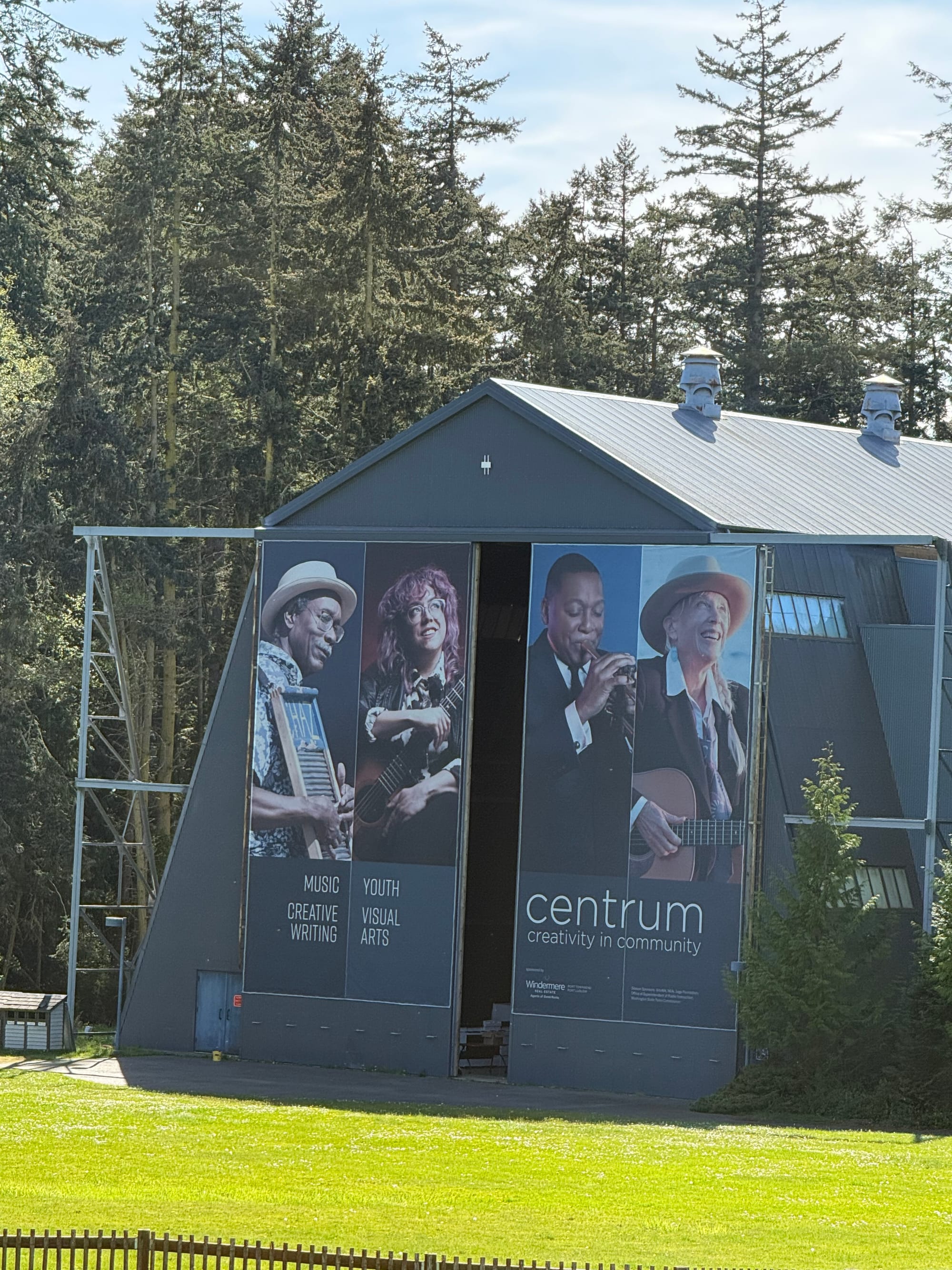 A large gray converted blimp hangar with large banners with four musicians hanging from the outside doors. 