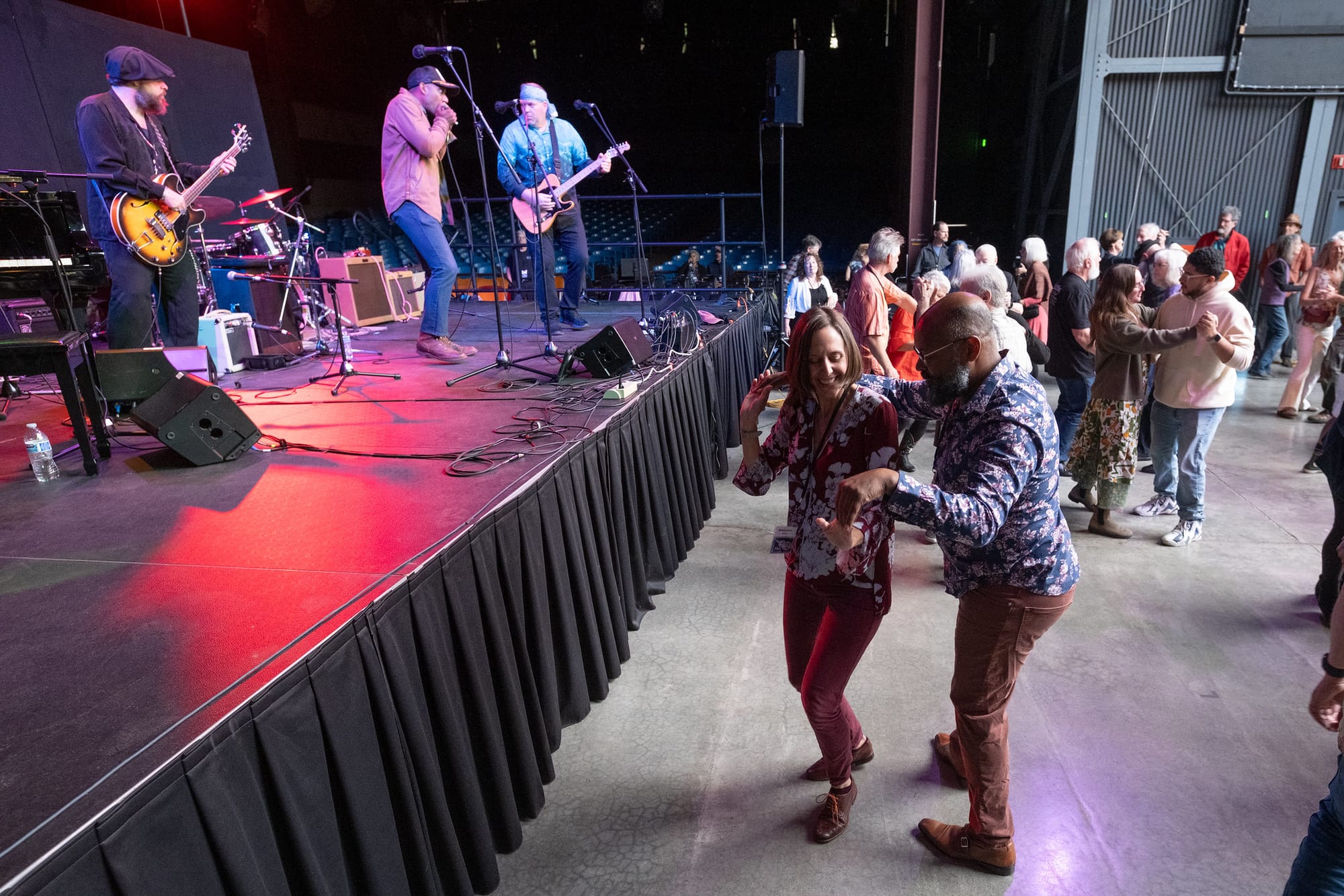 Damon and Kelsy Lynn Stone dancing with a band on a stage to the left and people dancing in the background.