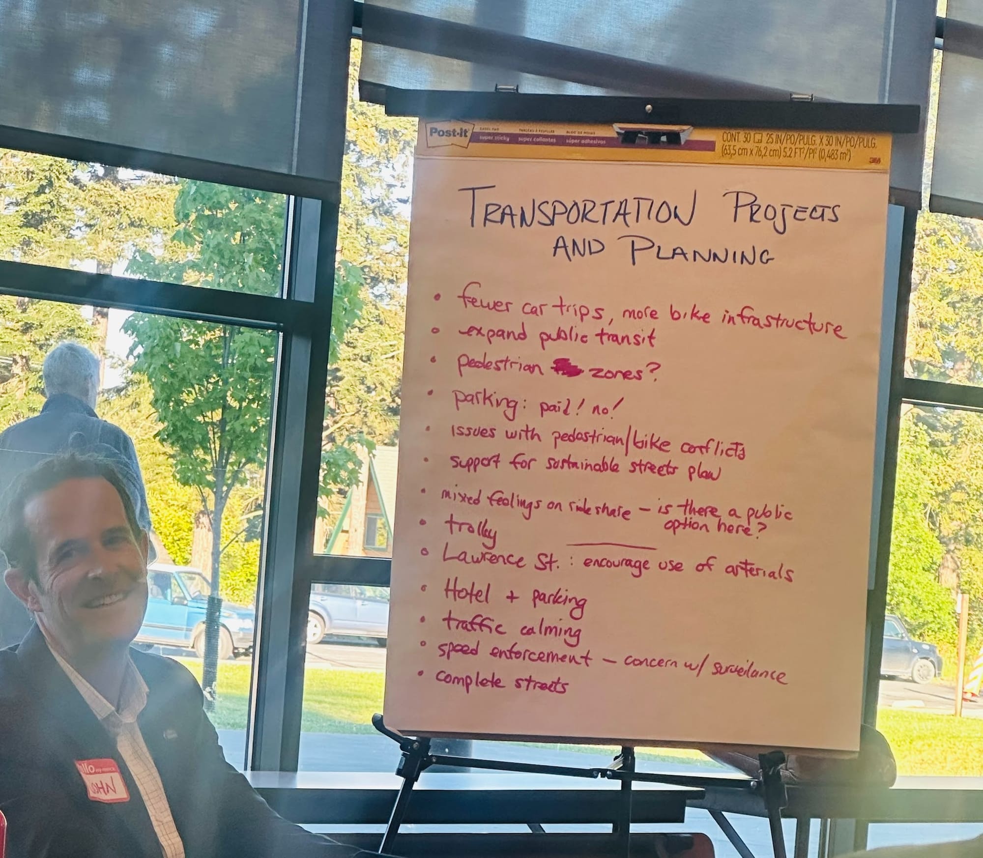 John Mauro in front of a large sheet of paper with Transportation Projects and Planning items listed. 