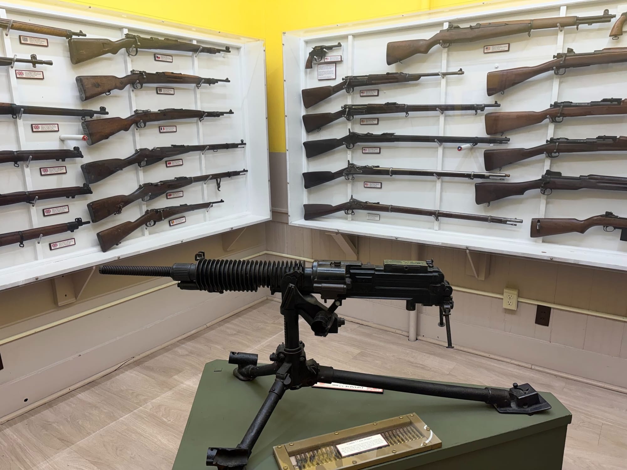 A collection of historical firearms including bolt-action rifles, revolvers and a Type 92 heavy machine gun in the center.