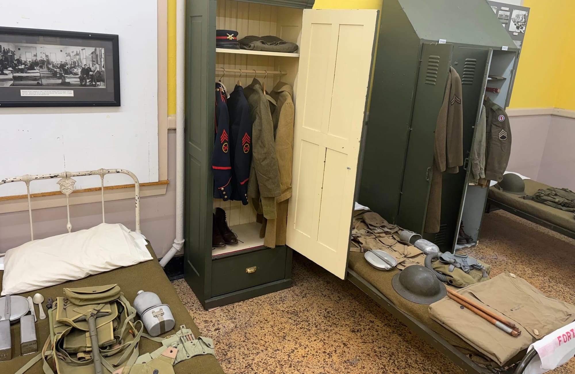 Military barracks exhibit with cots and lockers and examples of uniforms and equipment used.