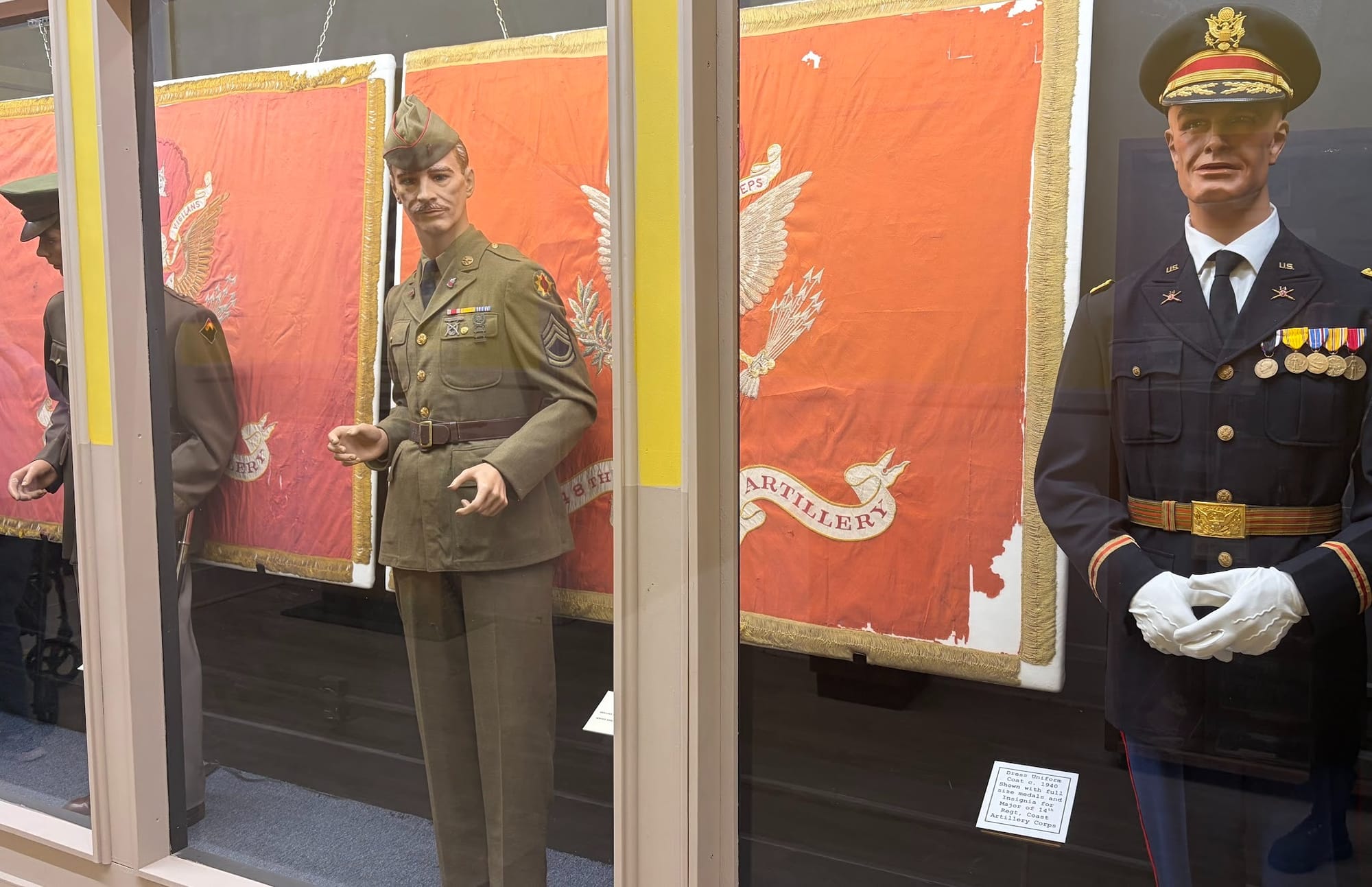 Three mannequins in military uniform behind glass.