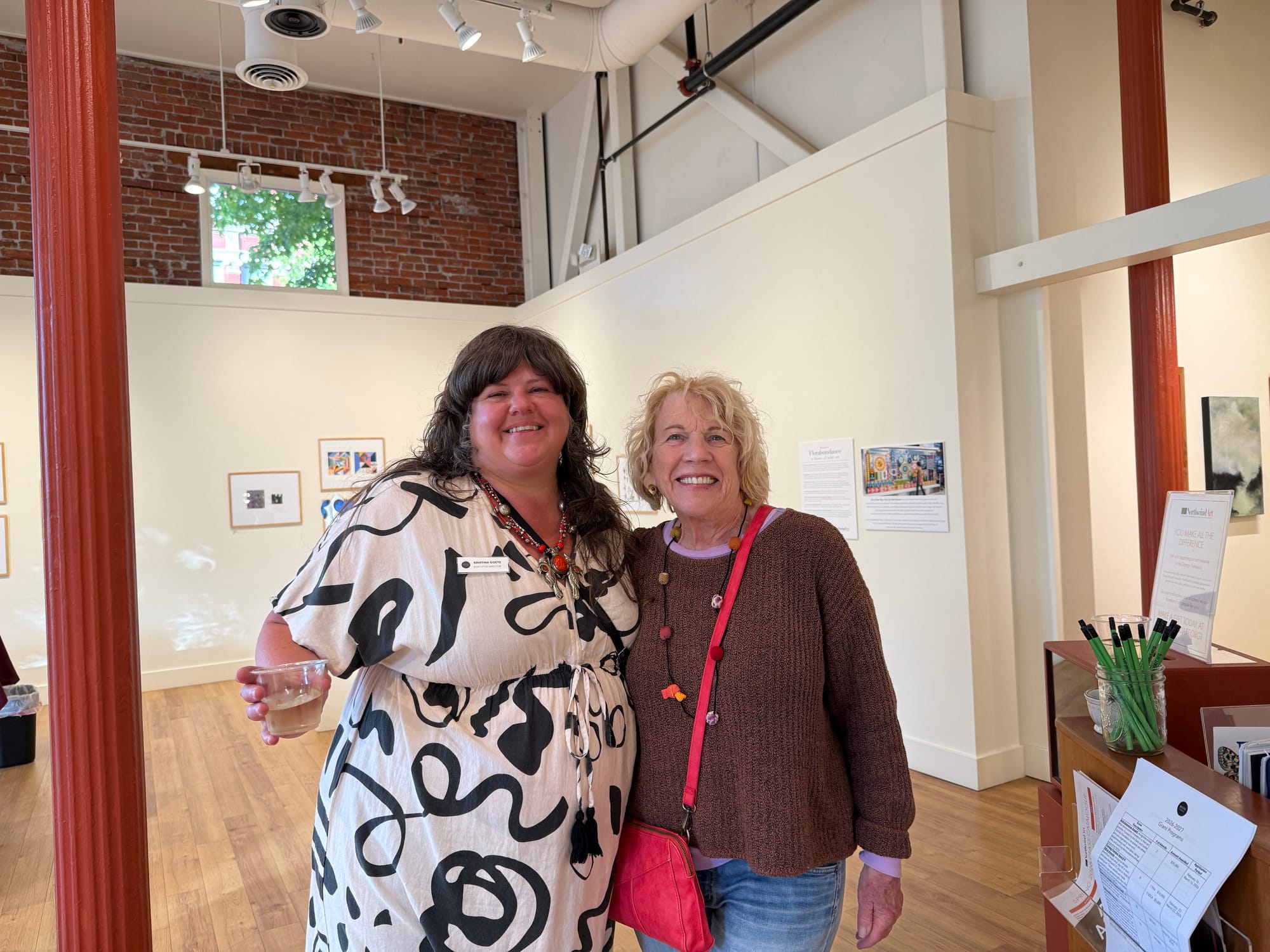 Kristina Goetz, left, and Lorraine Vagner, side embrace for a photo with the gallery behind.