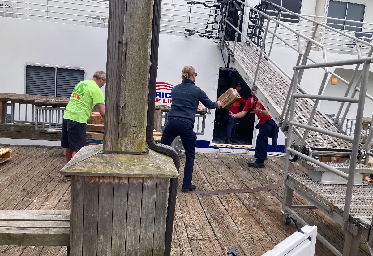 ACL workers tossing goods onto the ship in a port door under the gang plank.