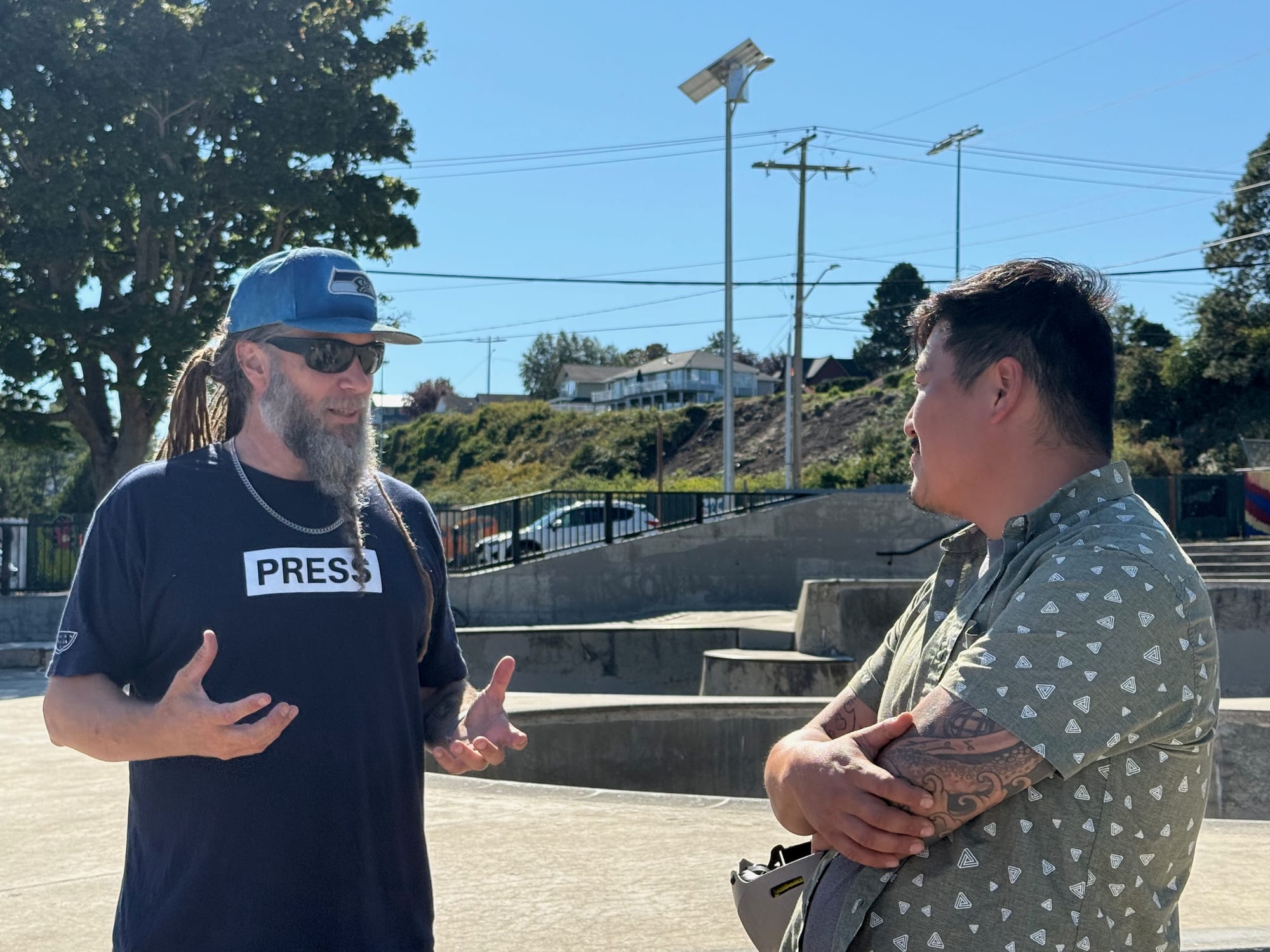 Jesse Joshua Watson, left, talks with skater Nam Siu, with skate park in the background.