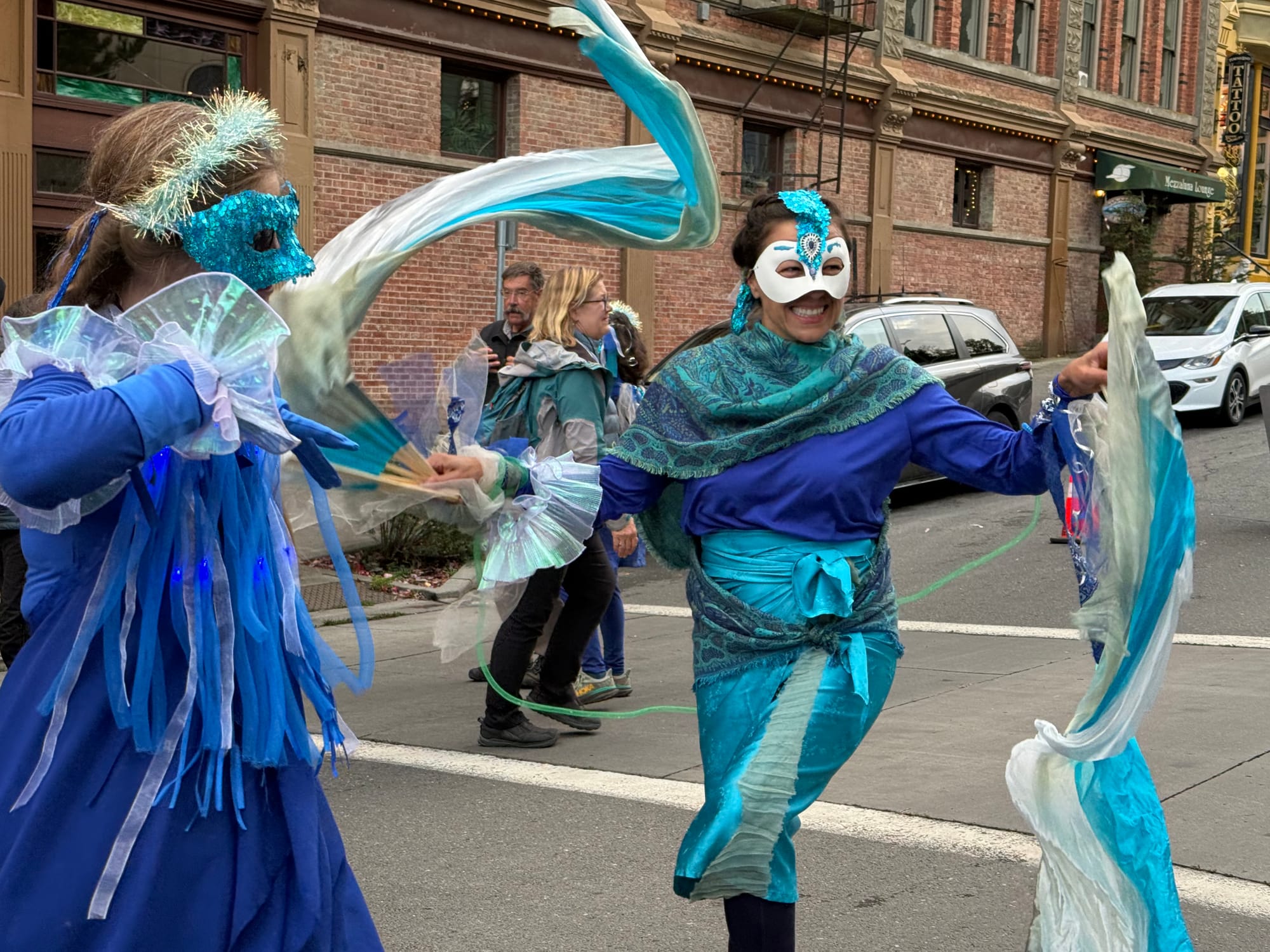 Patrizia Hironimus, right, joins an unidentified dancer in masks and blue flowing costumes on Taylor and Washington.