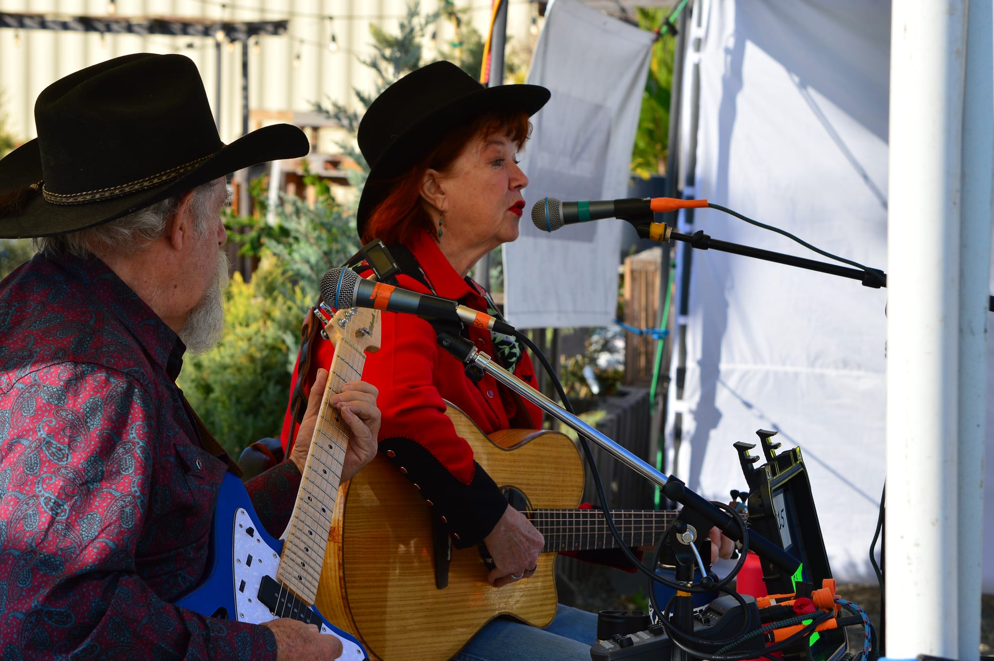 Jill McAnally, right, and Kevin McConnell, aka Jill and Kevin, playing guitars and singing into microphones. 