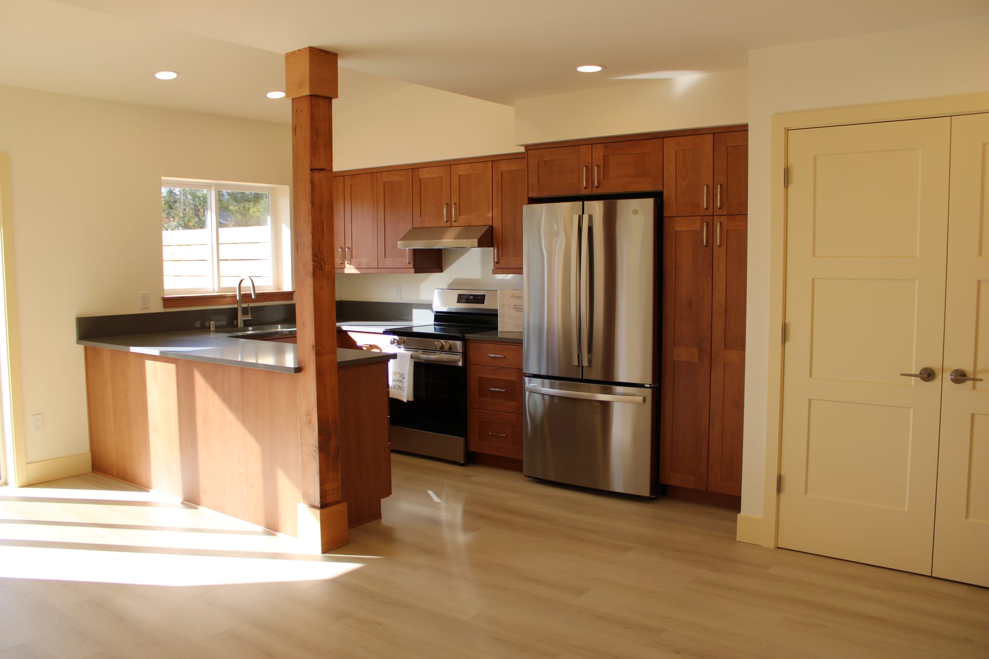 The kitchen inside of one of the 3-bedroom units with a bar and sink to the left, a silver refrigerator in the center and a closet to the right. 