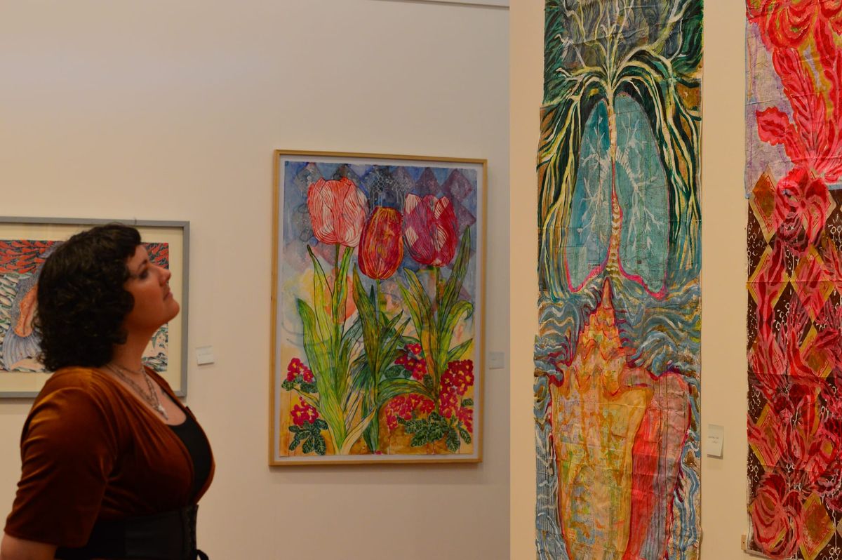 Davy Mack-Hazelwood beholds two of the vibrantly colorful paintings in Martha Worthley’s exhibit 