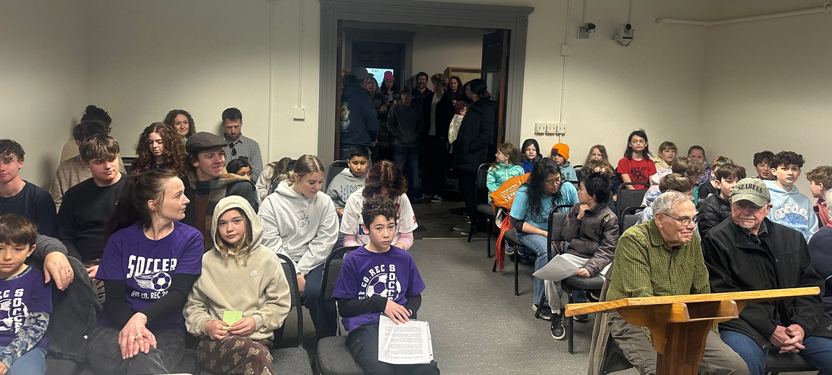 Youth and adult community members filling the County Commissioners Chambers and spilling into the hallway