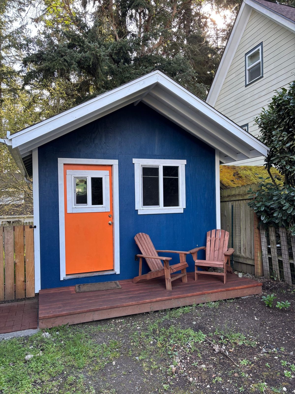A backyard shed with adirondack chair, blue shed, orange do