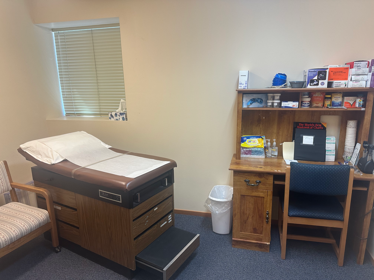 Exam room with an exam table to the left and a desk to the right.