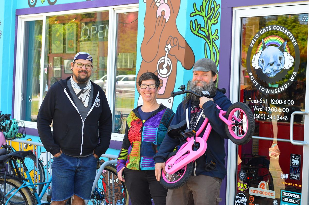 Gabe Quintanilla, left, Liz Arp and Jonathan Arp in front of their colorful bike shop, Jonathan, right, is holding a small pink bicycle.  