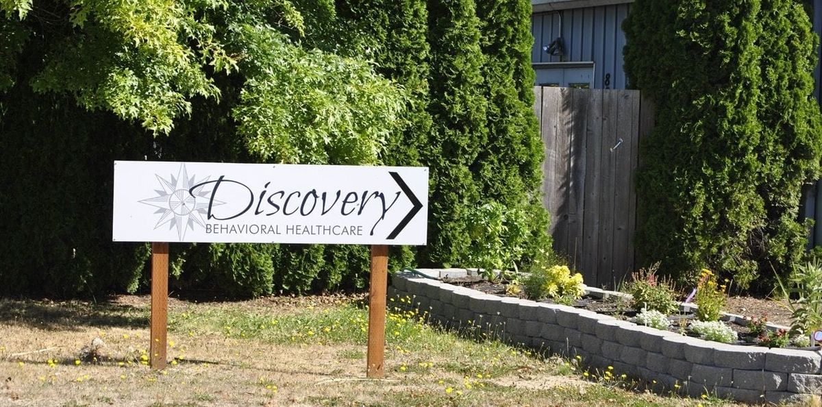 Discovery Behavioral Health (DBH) sign with a garden bed and greenery.
