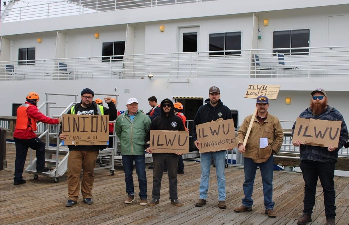 International Longshore and Warehouse Union members picketing American Cruise Lines, lined up on the Union Wharf next to a cruise ship. 