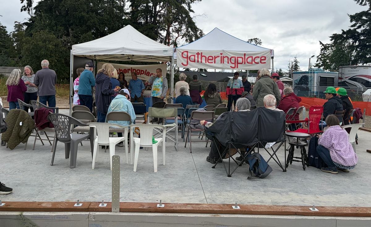 On the foundation slab there are rows of chairs in front of two tents with Gatheringplace banners. 