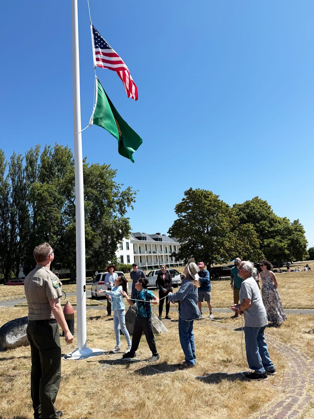 Mike Howard, his wife Carol and their grandchildren Abigail and Graham raise the flags on a new pole, Brian Hageman stands back to watch.