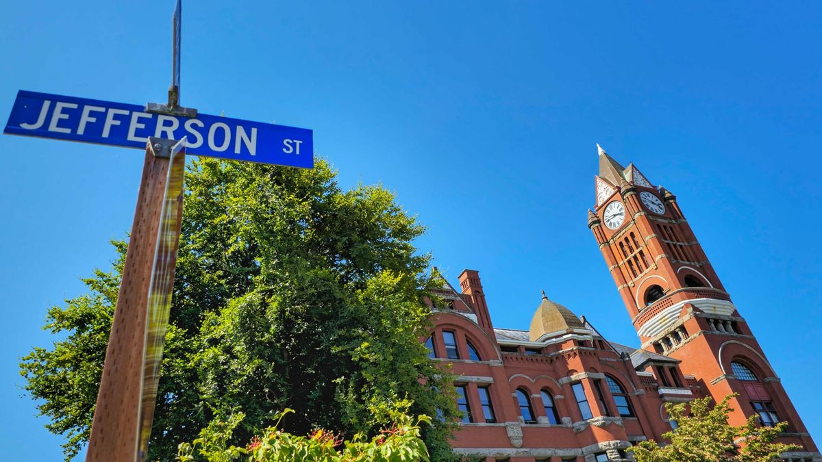 The Jefferson County Courthouse. A red brick building with a clock tower on the right side. The street sign for Jefferson Street is in the foreground.