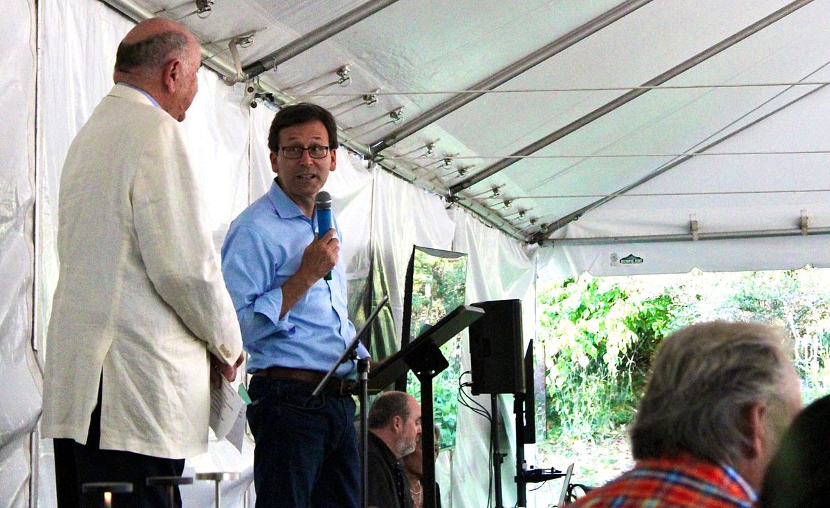 Bayside Housing and Services Executive Director Gary Keister, left and Governor Bob Ferguson speaking under a catering tent. 