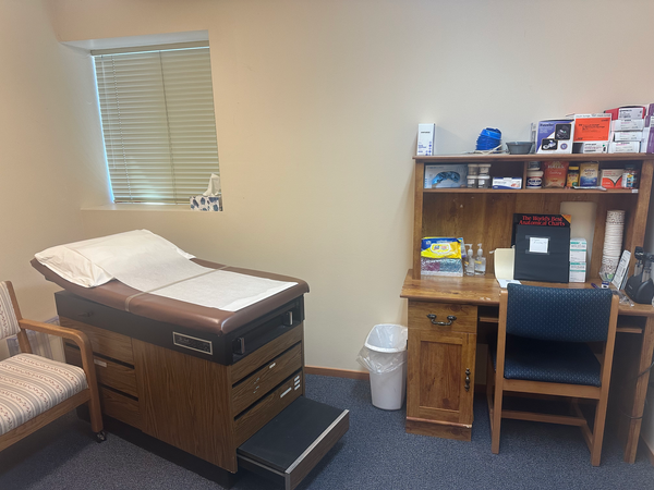 Exam room with an exam table to the left and a desk to the right.