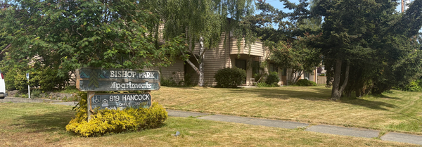 Bishop Park apartments sign in front of the apartment yard with trees in the foreground. 