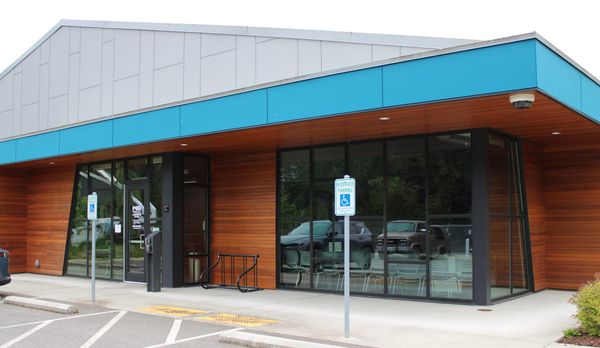 Jefferson County PUD building. Stained horizontal planks with large windows and a blue border around a gray roof peak