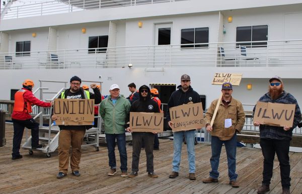 International Longshore and Warehouse Union members picketing American Cruise Lines, lined up on the Union Wharf next to a cruise ship. 