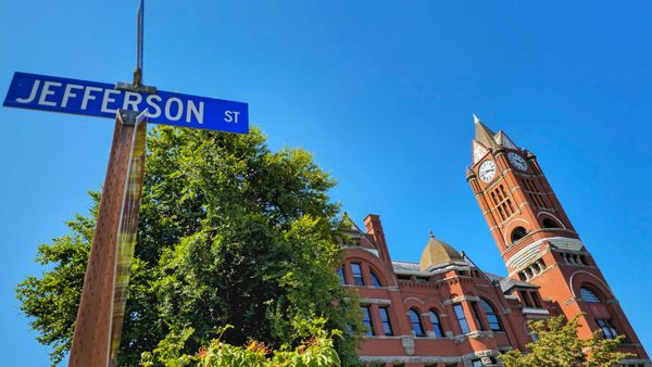 The Jefferson County Courthouse. A red brick building with a clock tower on the right side. The street sign for Jefferson Street is in the foreground.