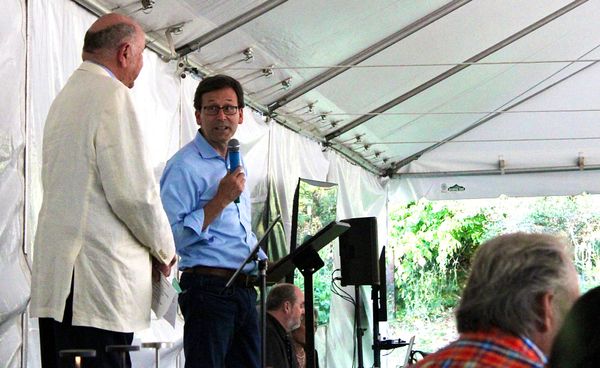 Bayside Housing and Services Executive Director Gary Keister, left and Governor Bob Ferguson speaking under a catering tent. 