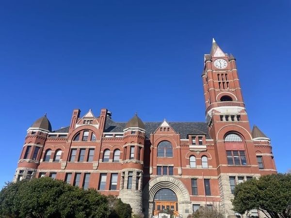 The Jefferson County Courthouse, Port Townsend, Washington. A large red brick building with a clock tower on the right side. 