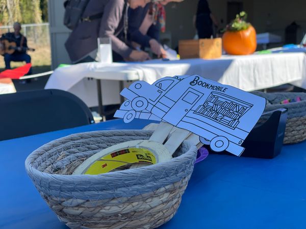 Paper mini bookmobiles on a stick in a basket available for coloring. 