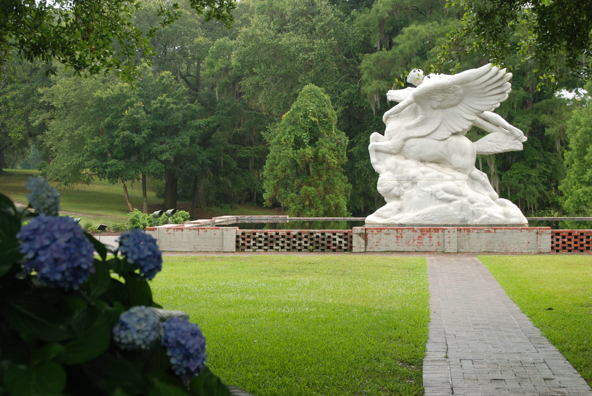Massive statue of person riding a winged horse within a garden setting