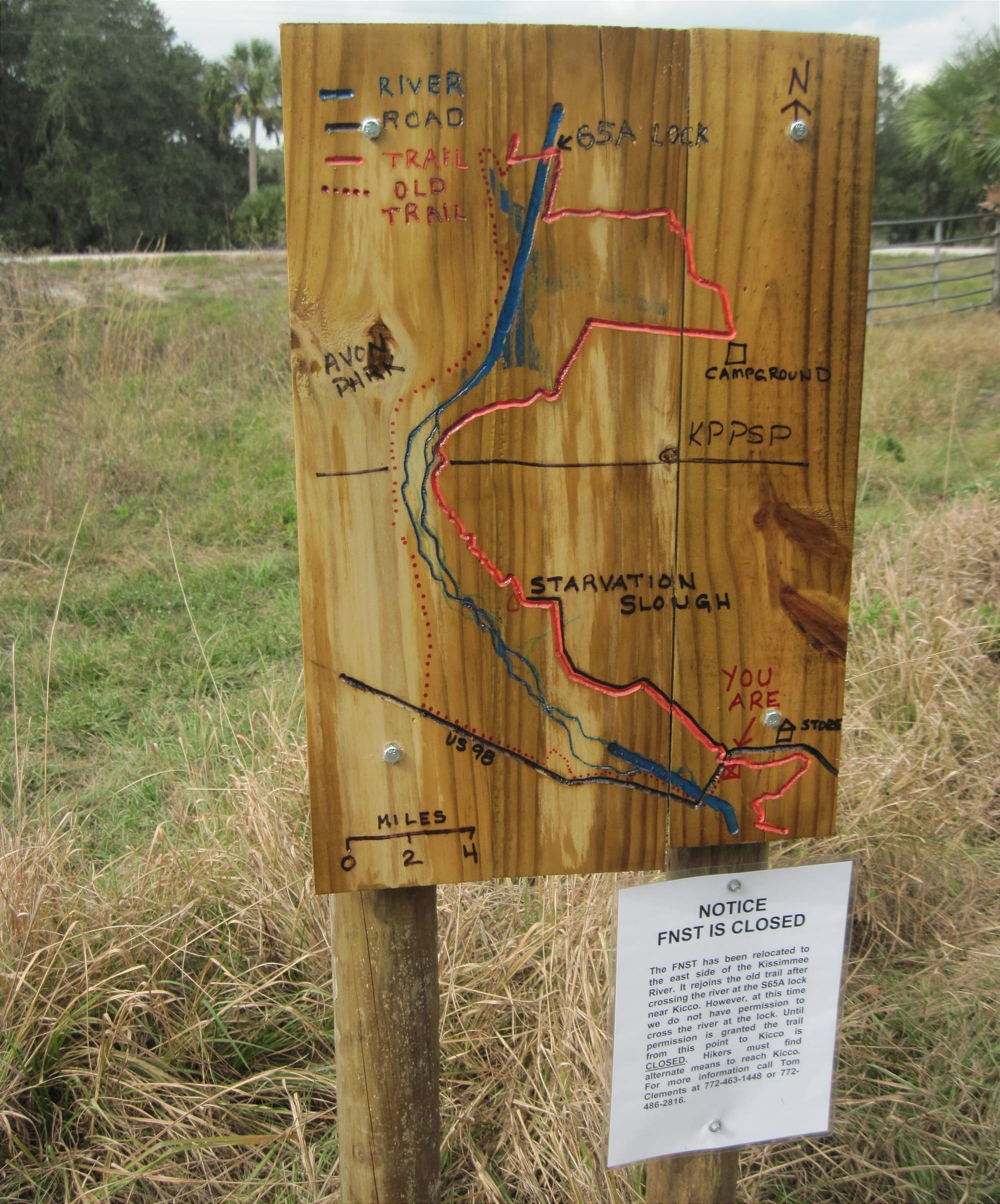 Wooden routed sign showing trail map and warning