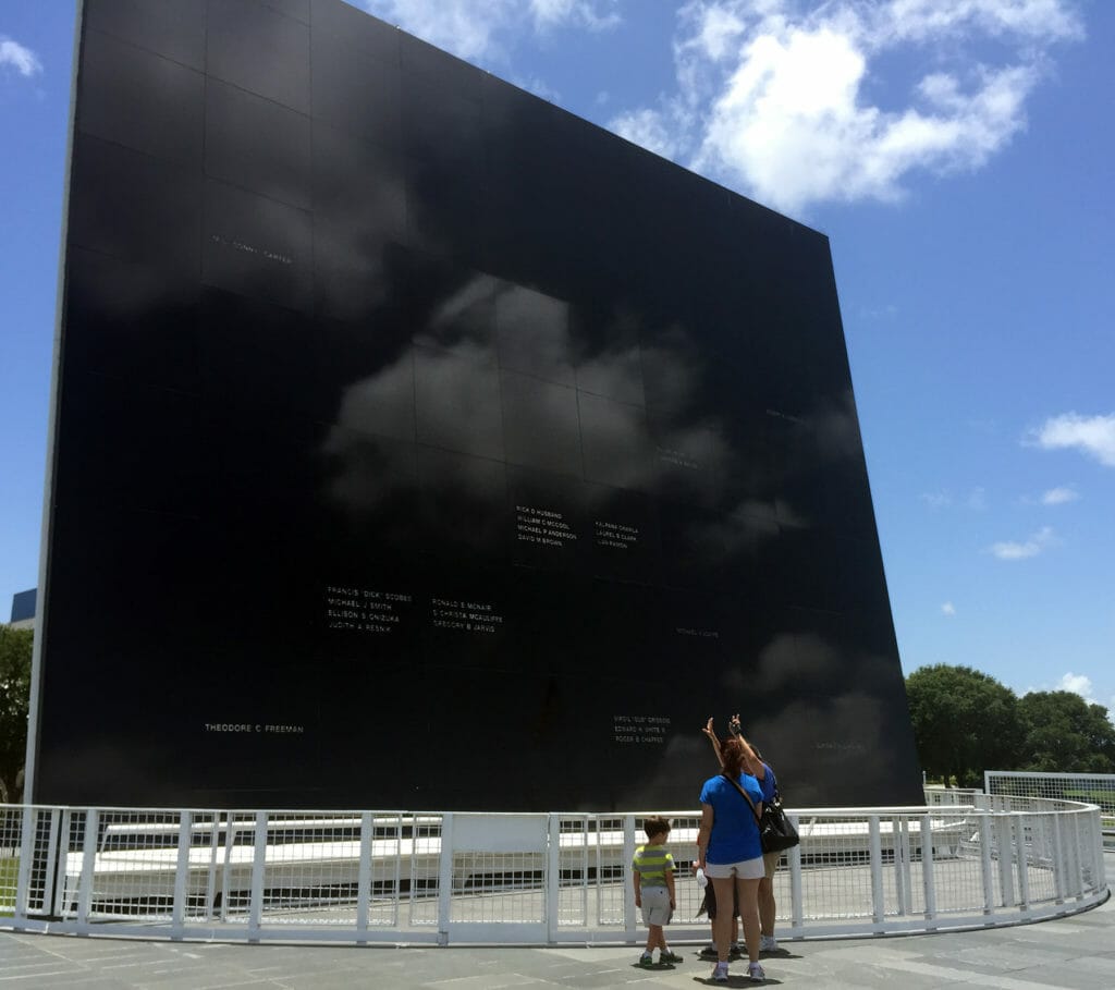 Visitors looking at the towering dark slab of granite making up the astronaut memorial