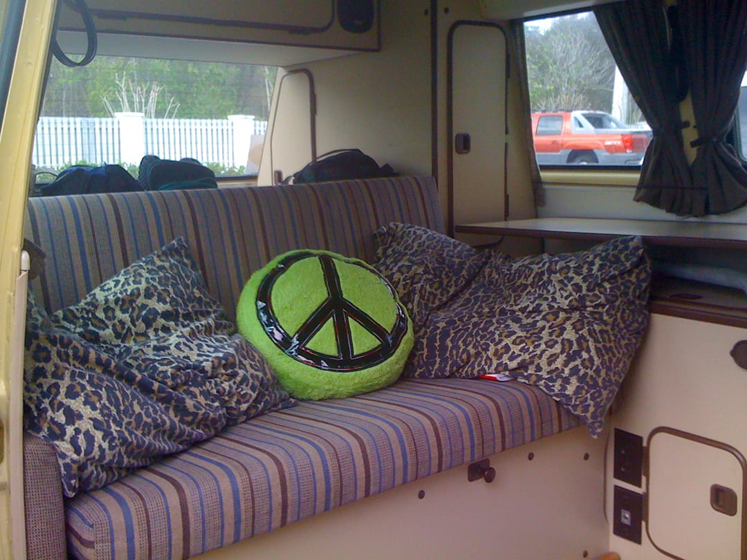 Pillows and a peace sign pillow on the back bench of our camper van