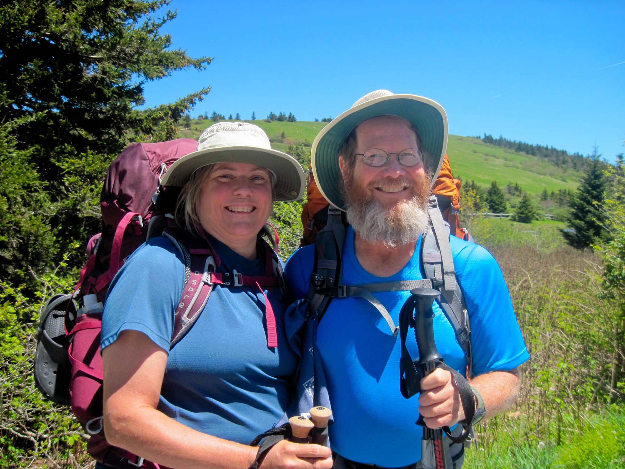 Woman and man backpackers with mountain bald behind them