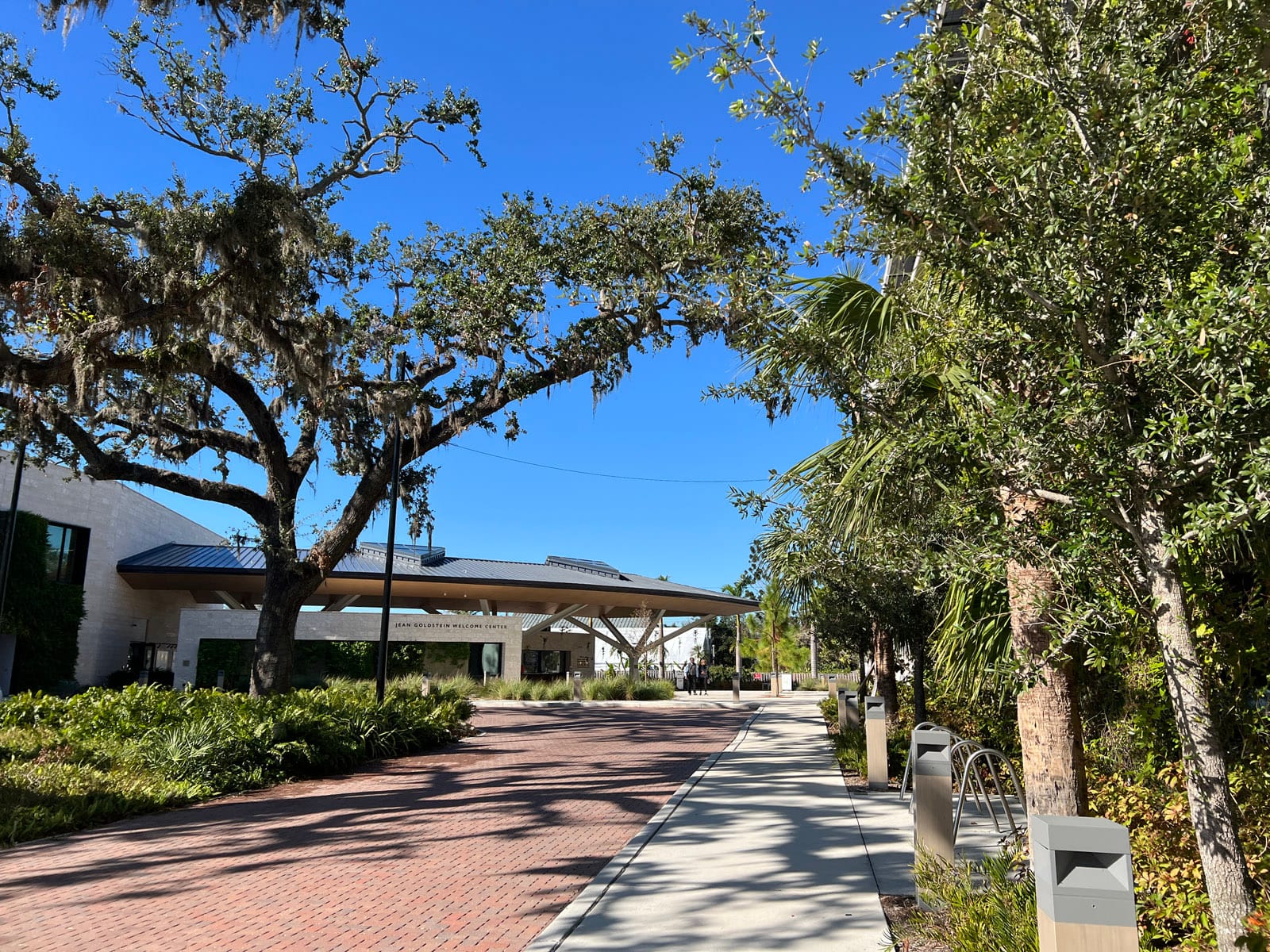 Brick road and sidewalk amid greenery leading to roofed pavilion