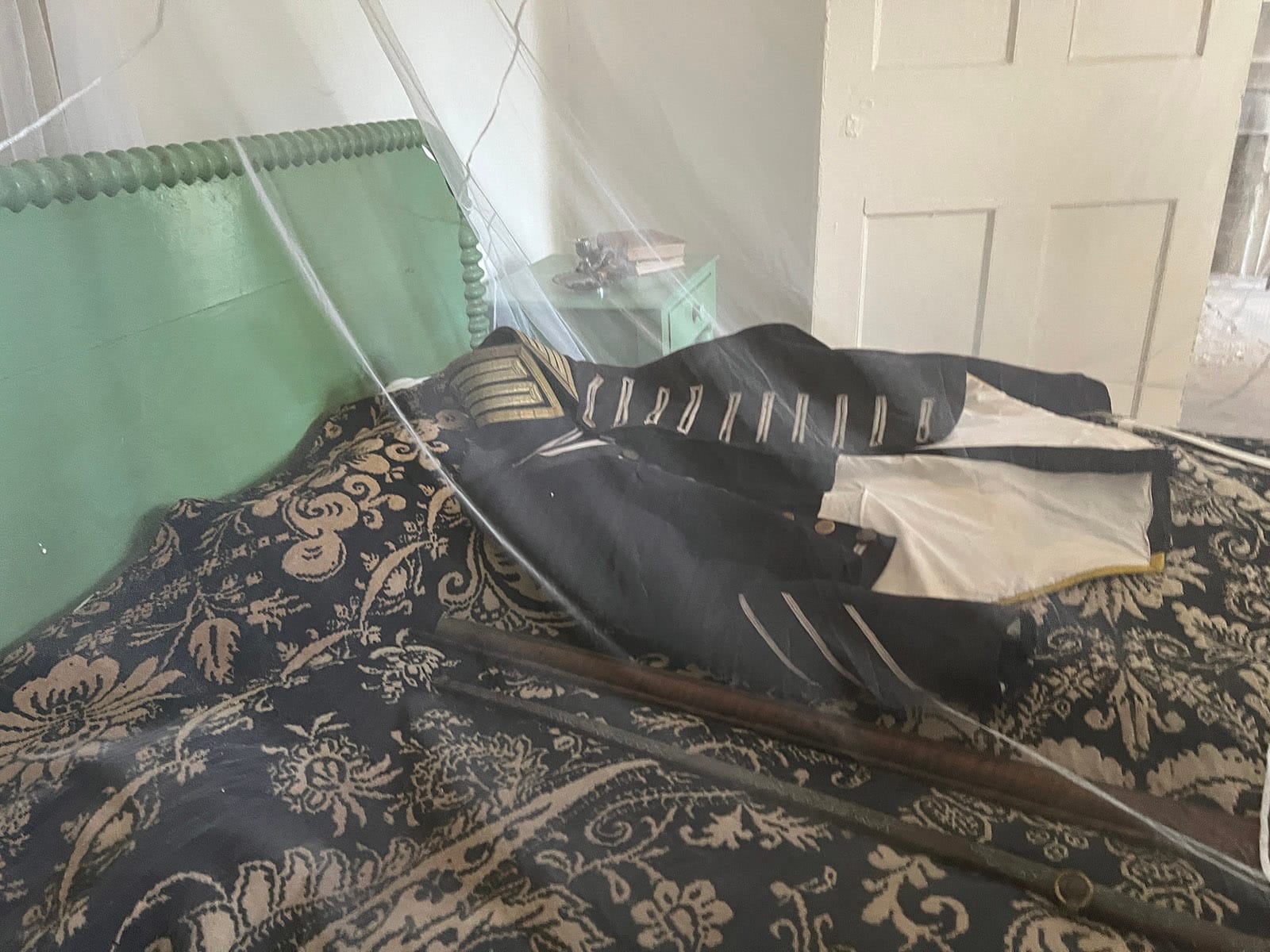 Military jacket and coverlet in indigo under a sheen of mosquito netting.