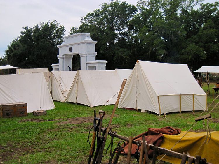 Canvas tents crowded together on mud and grass