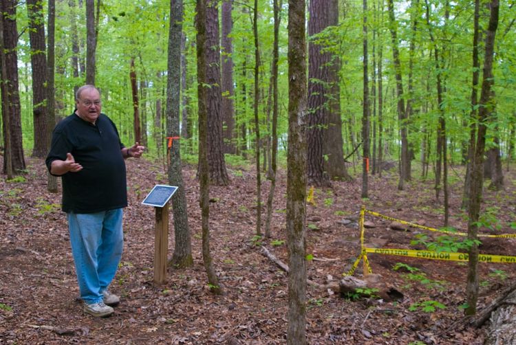 A man standing next to an interpretive sign in a forest