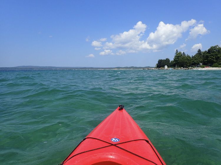 Bow of kayak in a lake facing rocky shoreline