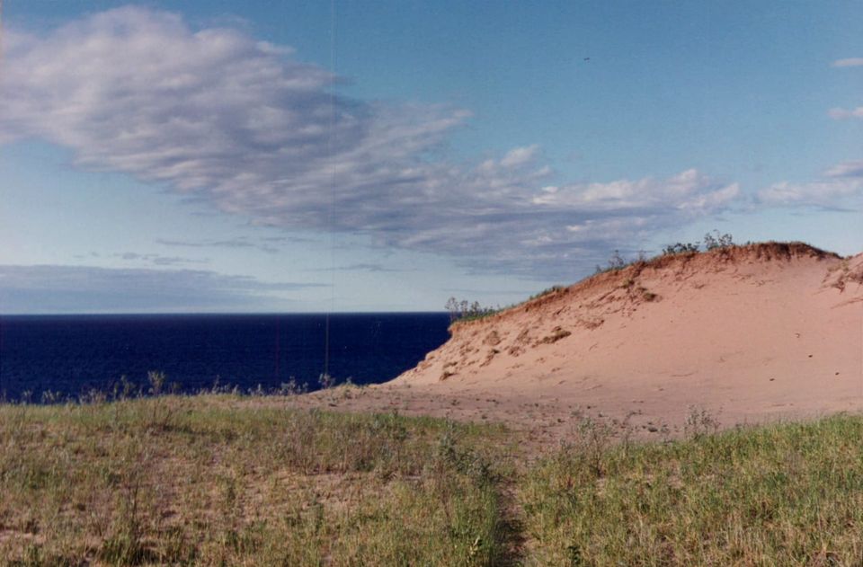 Dune with grass below and lake horizon beyond