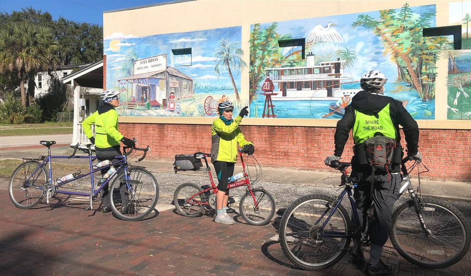 Cyclists looking at a colorful mural along a brick street