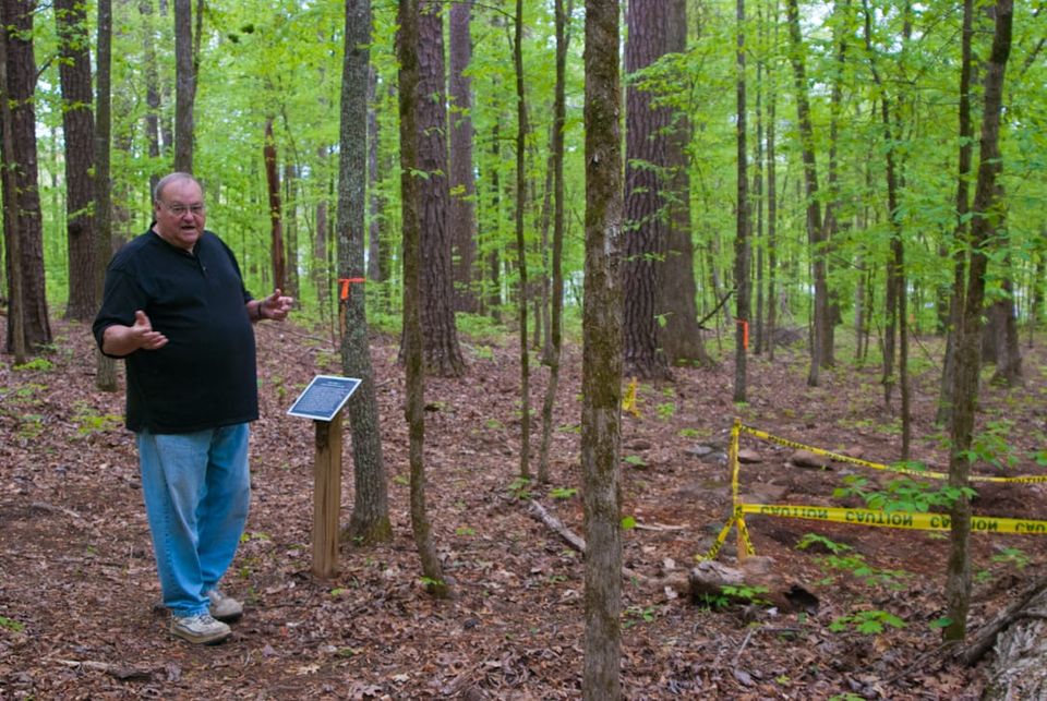 A man standing next to an interpretive sign in a forest