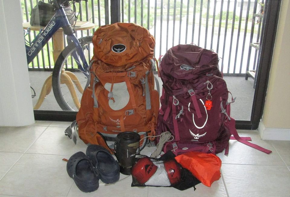 Two backpacks and related gear against a porch sliding door