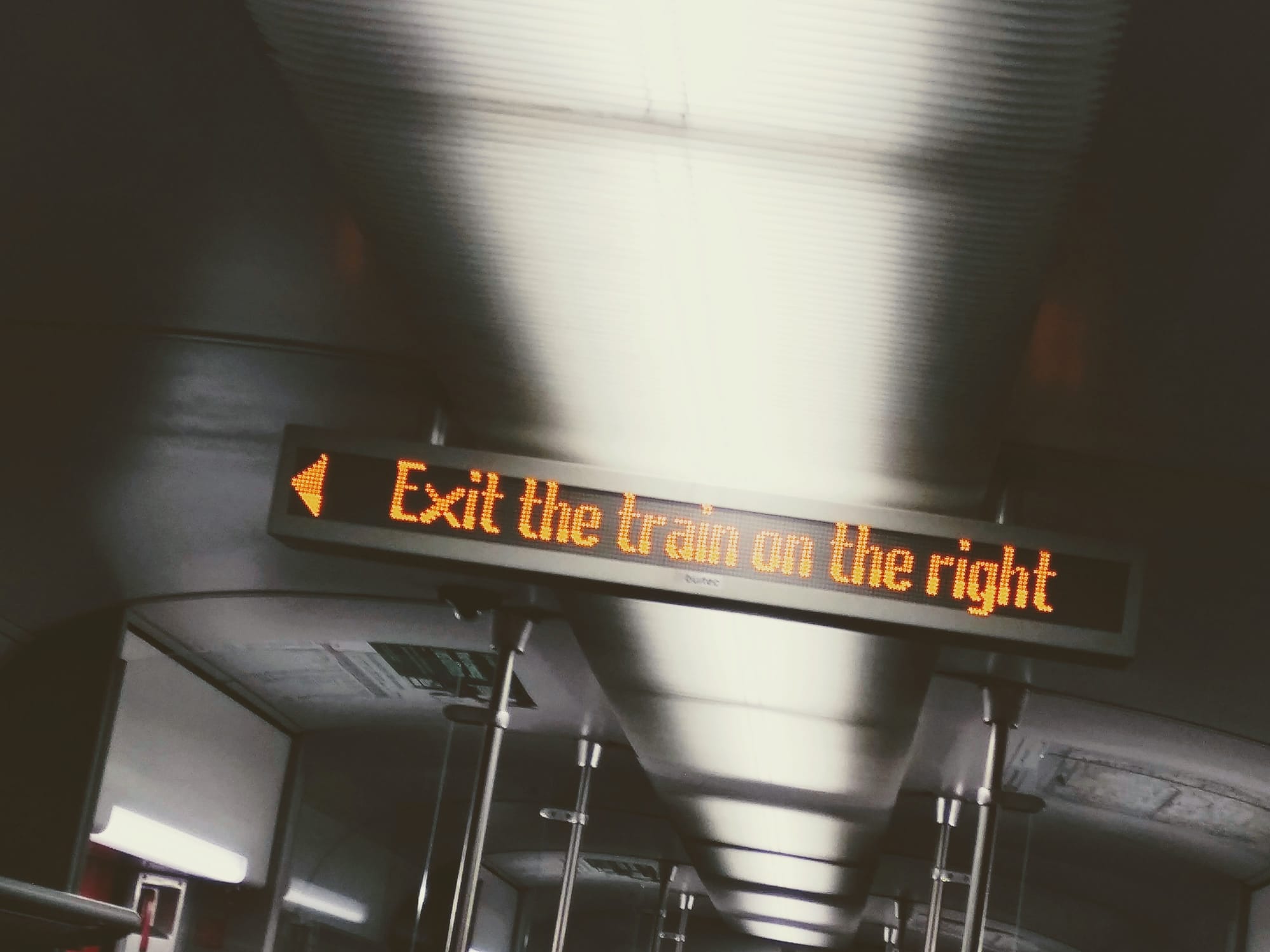 A photograph of an information display on a train which reads, "<< Exit the train on the right"