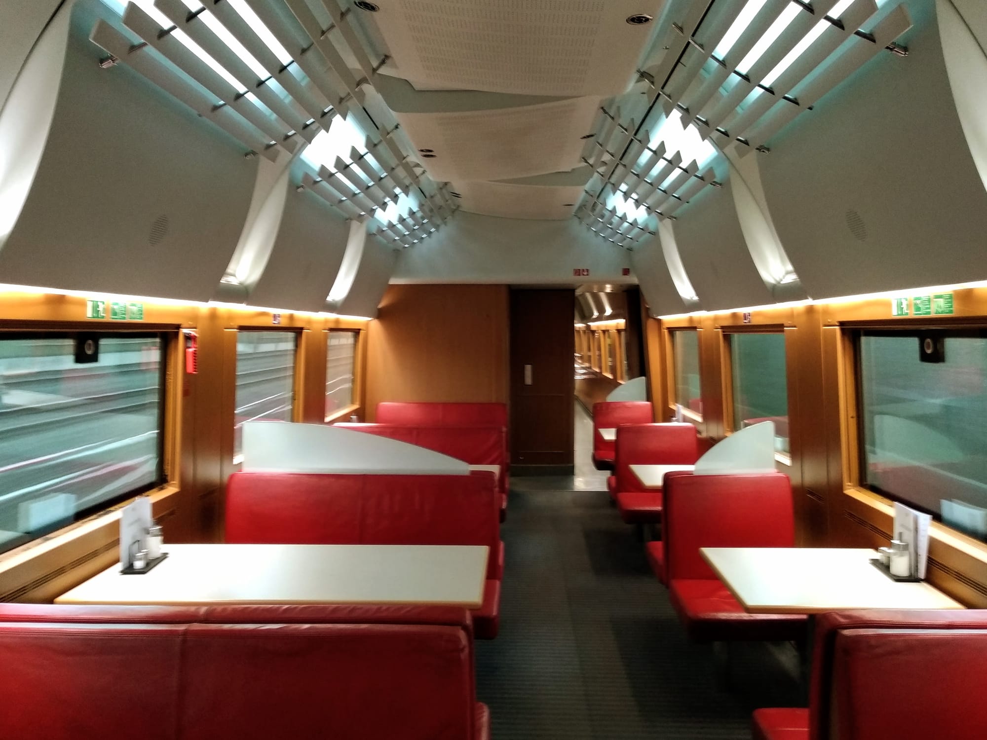 Railway infrastructure blurs bast the empty interior of a Deutsche Bahn dining car.